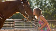 A young girl kisses a horse's nose.