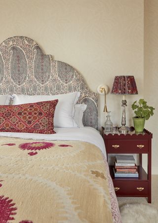 yellow bedroom with paisley headboard, red bedside, yellow patterned throw, patterned red cushion