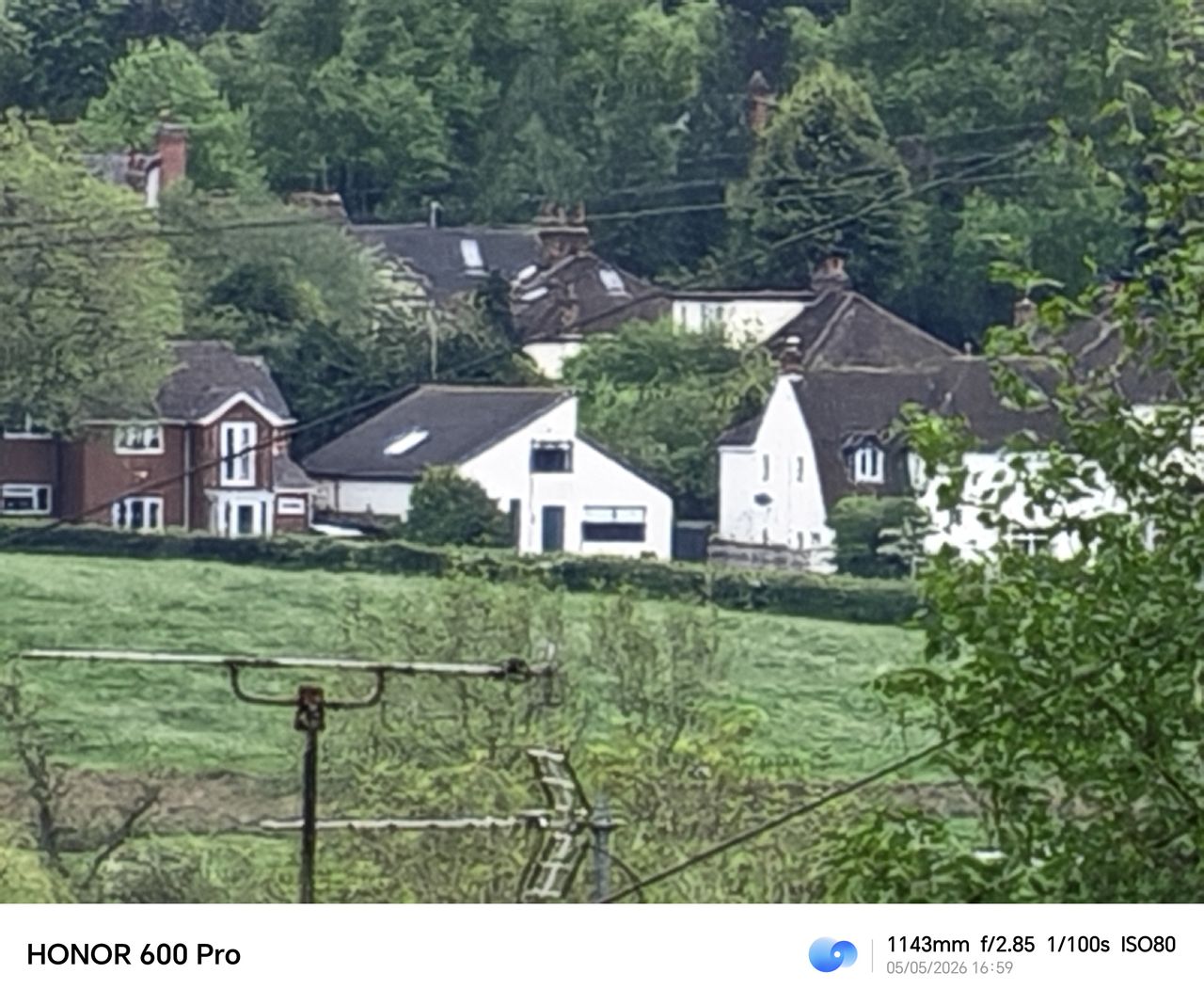 Heavily zoomed Honor 600 Pro image of distant white houses across a green field