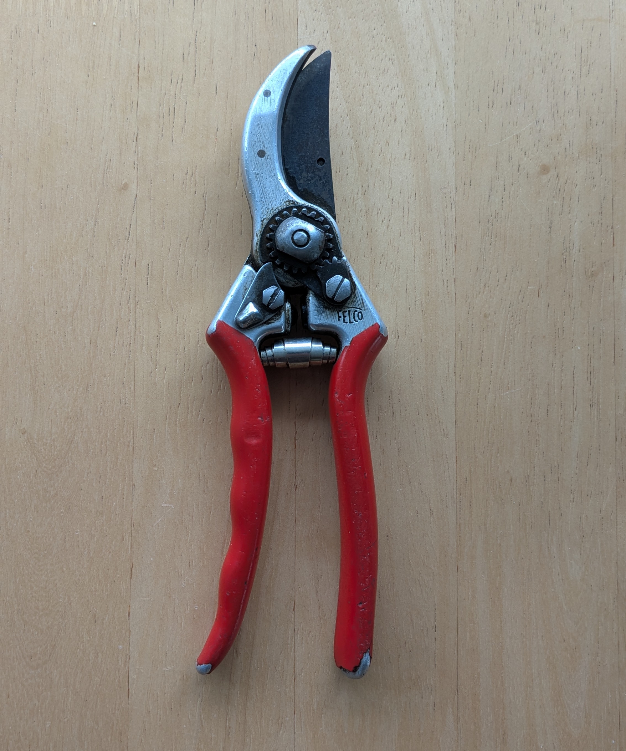 A pair of well-used Felco F2 pruners on a wooden background
