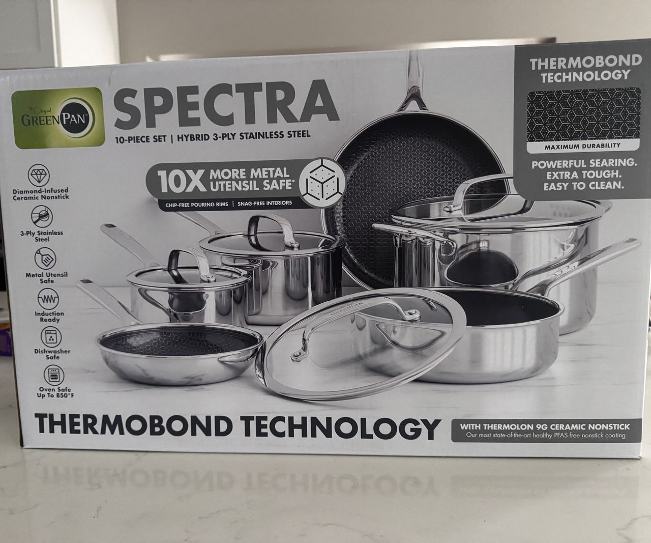 The full Greenpan Spectra Thermobond pan set in the white box on a kitchen counter.