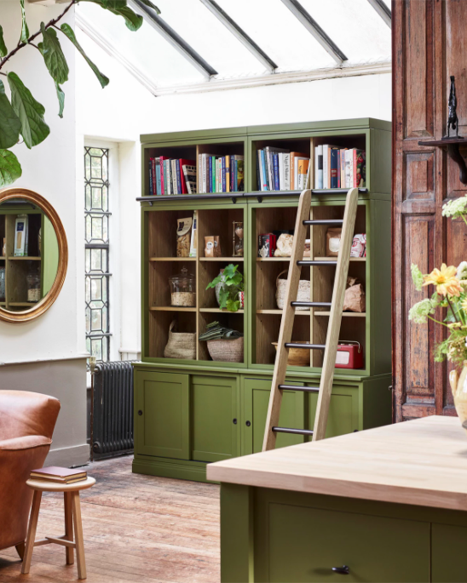 Kitchen diner with olive green dresser set against the wall below a glazed roof