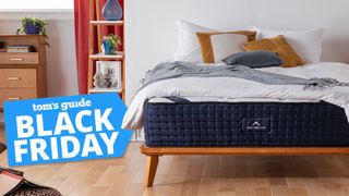 The DreamCloud mattress placed on a light wooden bedframe with a blue Black Friday sale bade overlaid on the image