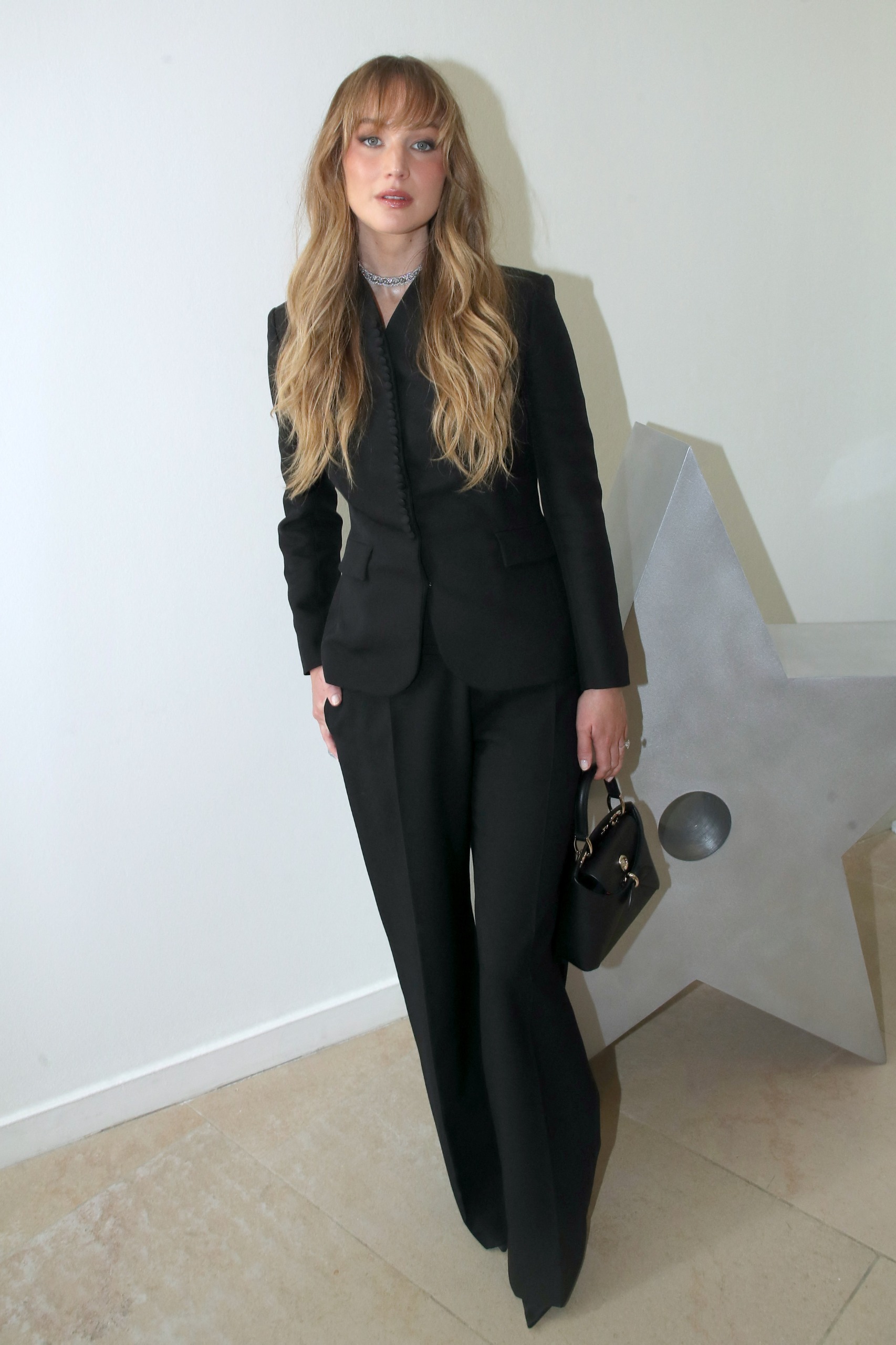 Jennifer Lawrence wearing a black Dior suit and carrying a Dior bag