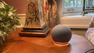 The Amazon Echo Dot (2020) pictured on a wooden table next to a lamp