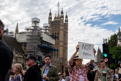 Anti-monarchy protester holding sign.