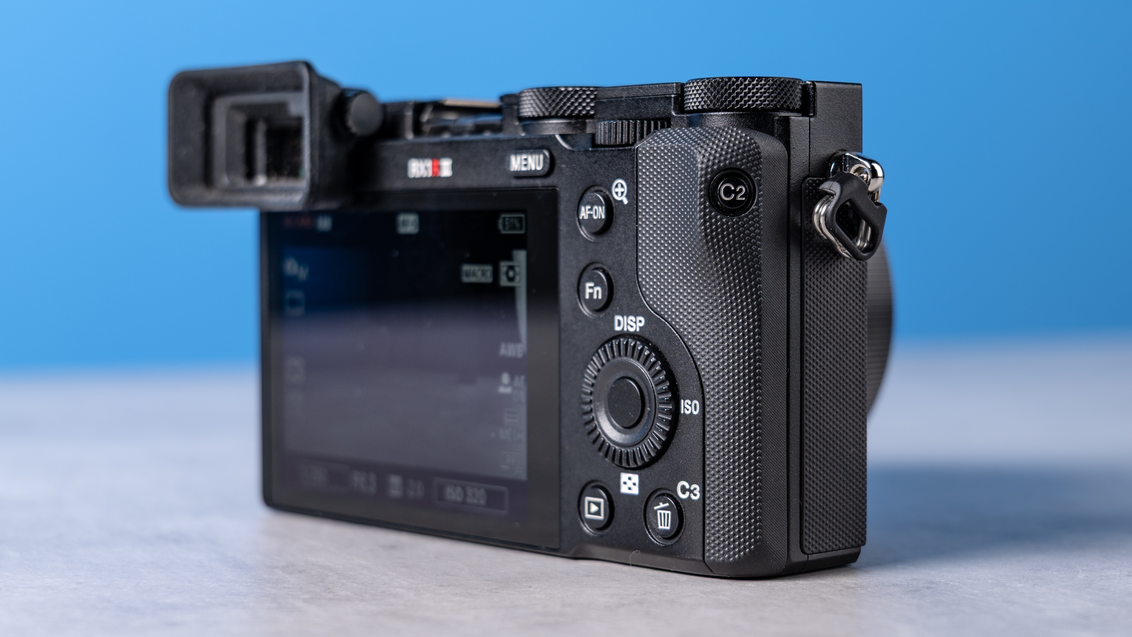 A photo of the Sony RX1R III on a stone surface with a blue background