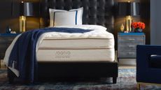 Where to buy a Saatva mattress: image shows the Saatva Classic Luxury Firm on a black bed frame with a blue throw draped across it