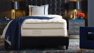 DreamCloud vs Saatva: The Saatva Classic Luxury Firm placed on a dark faux leather bed frame and covered with a blue throw