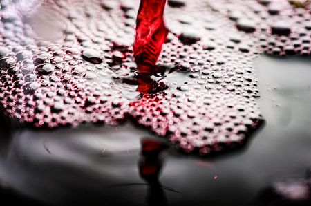 Pouring red wine making bubbles to let wine breath