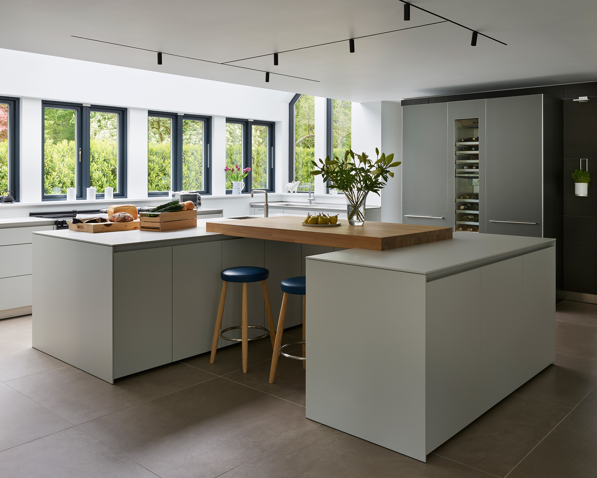 Kitchen trends 2021 showing a double island with simple wooden bar stools and a wooden worktop