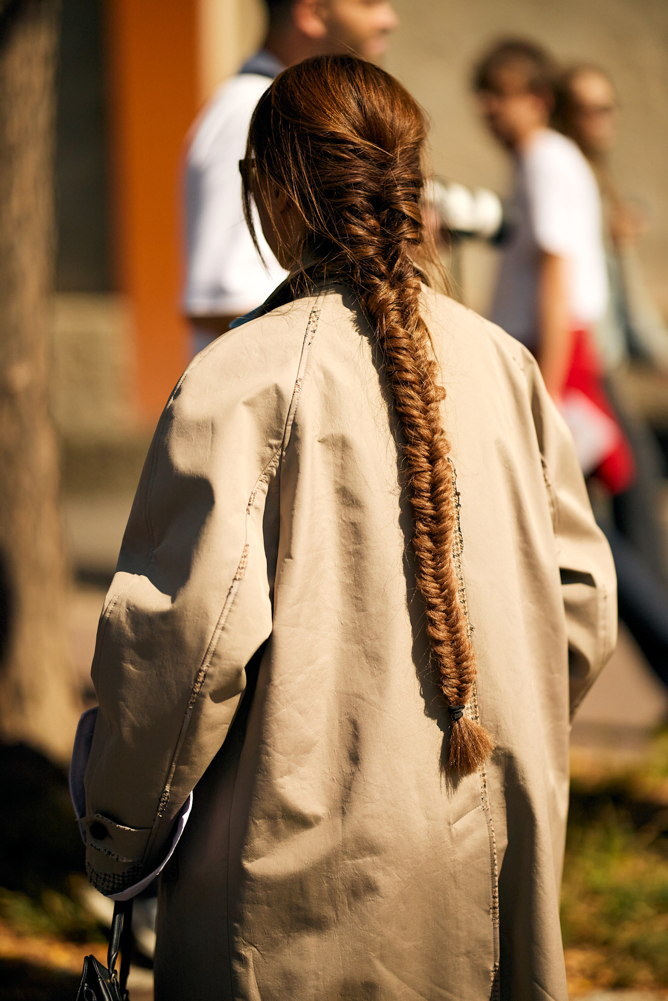 the back of a woman's body with a long fishtail braid and a tan coat