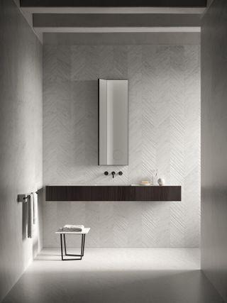 A white bathroom with textured tiles and a dark wood counter top