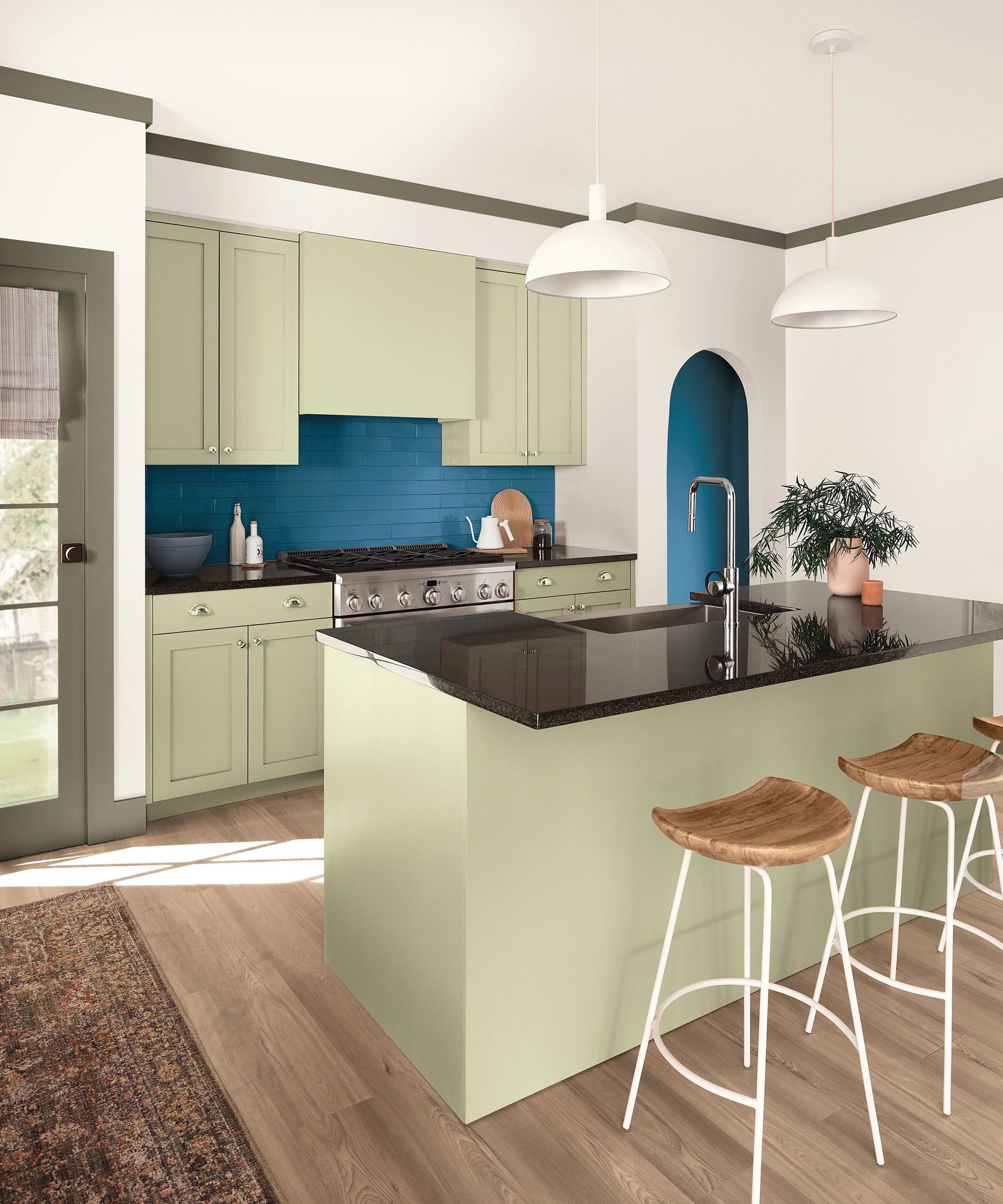 Kitchen with cabinetry painted in Sherwin-Williams' Celery, a dark blue tiled backsplash and arched doorway, two white pendant lights above the island, and wooden bar stools underneath.