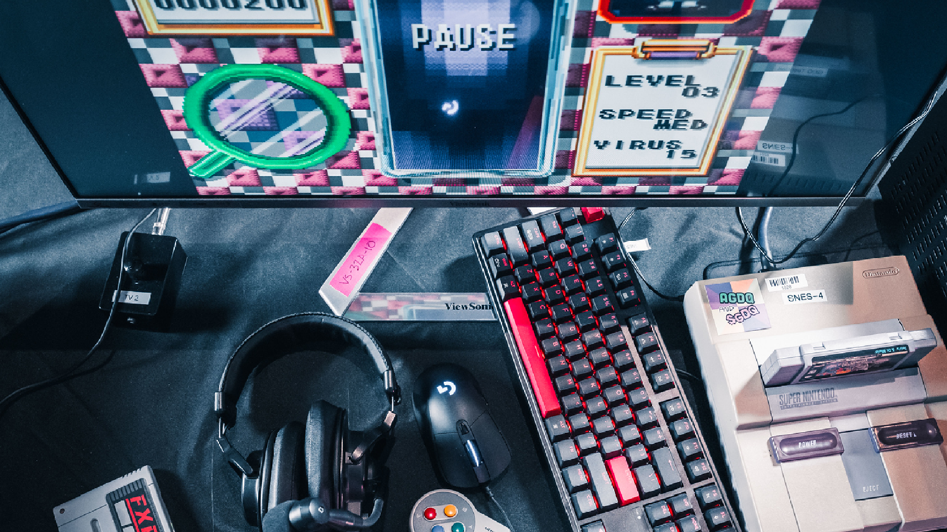 A photo showing a console, a keyboard, and several gaming accessories ready for Games Done Quick.