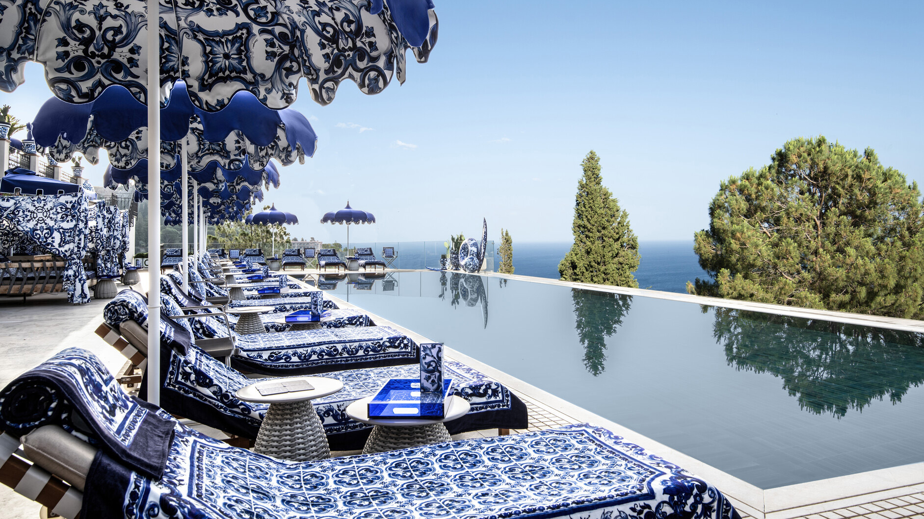 Blue and white patterned sun loungers next to a glassy swimming pool