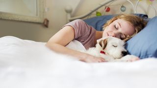 Woman sleeping with her pet dog in bed 