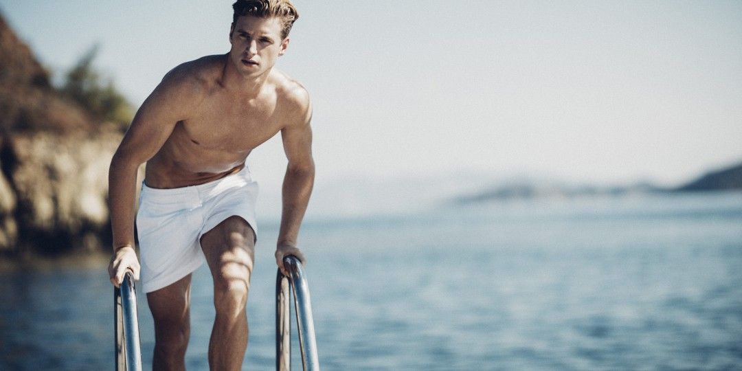 A man getting out of a swimming pool wearing the best swim trunks for men