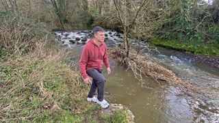 Man in front of a waterfall wearing Merrell SpeedArc Surge Boa walking shoes