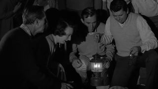 A group of people gathered around a body in The Twilight Zone Episode The Monsters Are Due on Maple Street