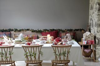 Long dining table dressed for a woodland christmas party theme with mistletoe tied to the back of the dining chairs