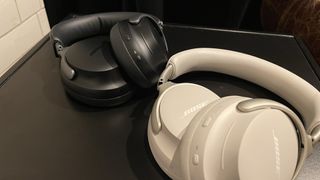 Black and white pairs of Bose QuietComfort Ultra Headphones lying on a black surface