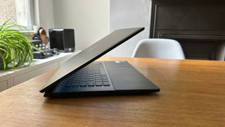 Side-view of a half-closed Dell Inspiron 16 Plus 7620 sitting on a wooden table