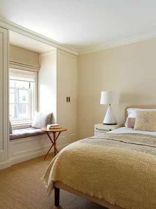 Beige bedroom with a window seat designed by Thurstan