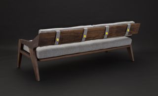 Dark wood bench with grey upholstery, fastened to the back of the bench with four yellow buttons