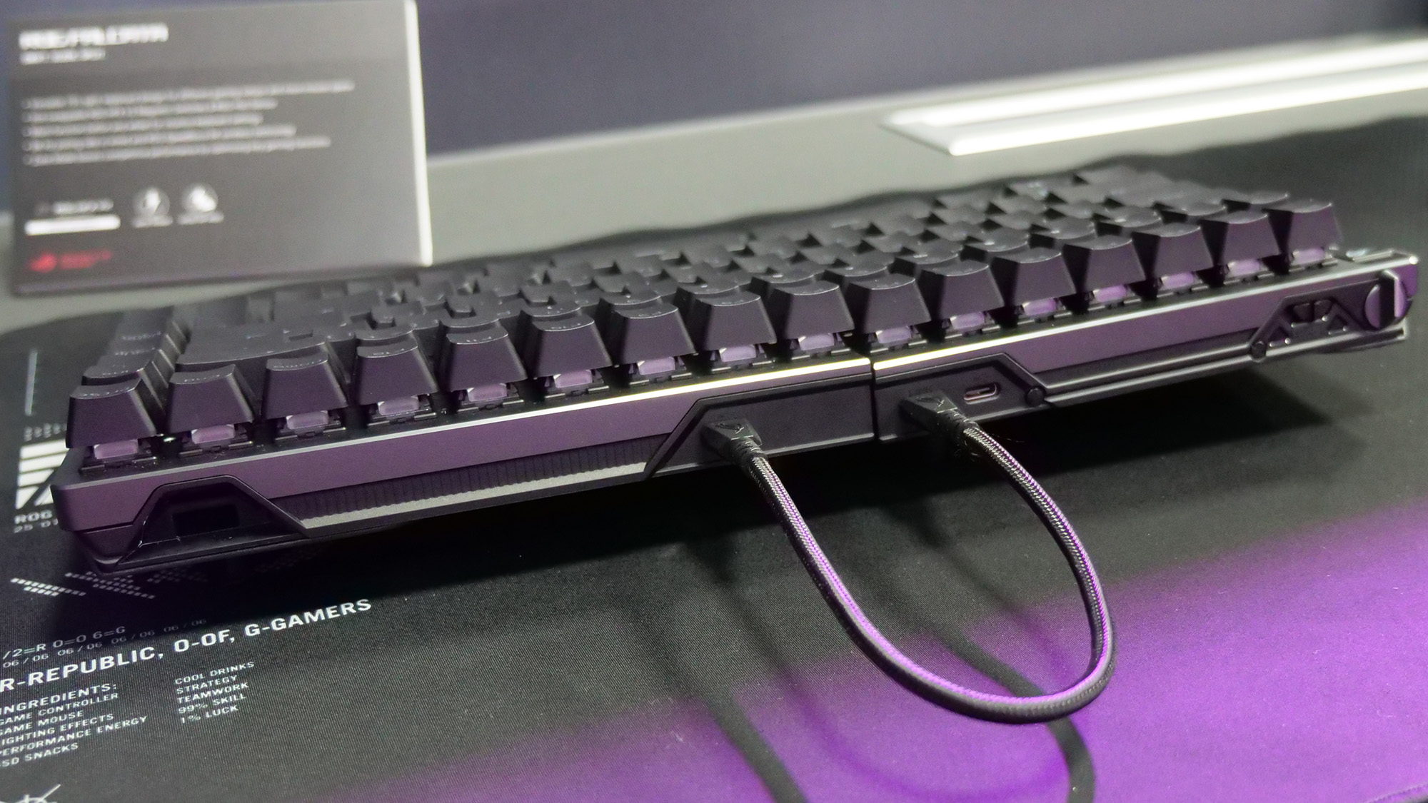 Asus ROG Falcata gaming keyboard on a large mousepad, viewed from the back to show connected USB-C cable.