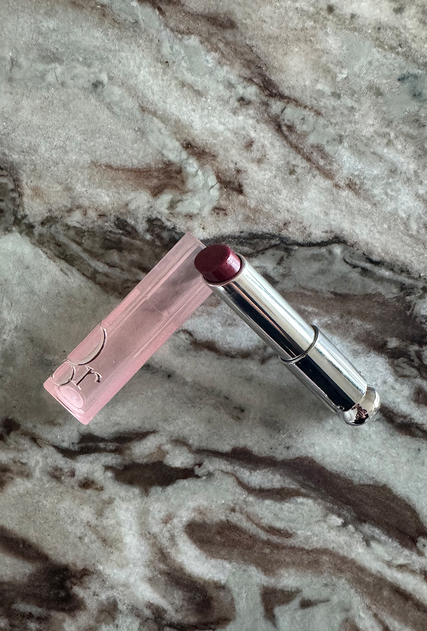 A close up of Dior Addict Lip Glow lip balm in Berry on a marble table