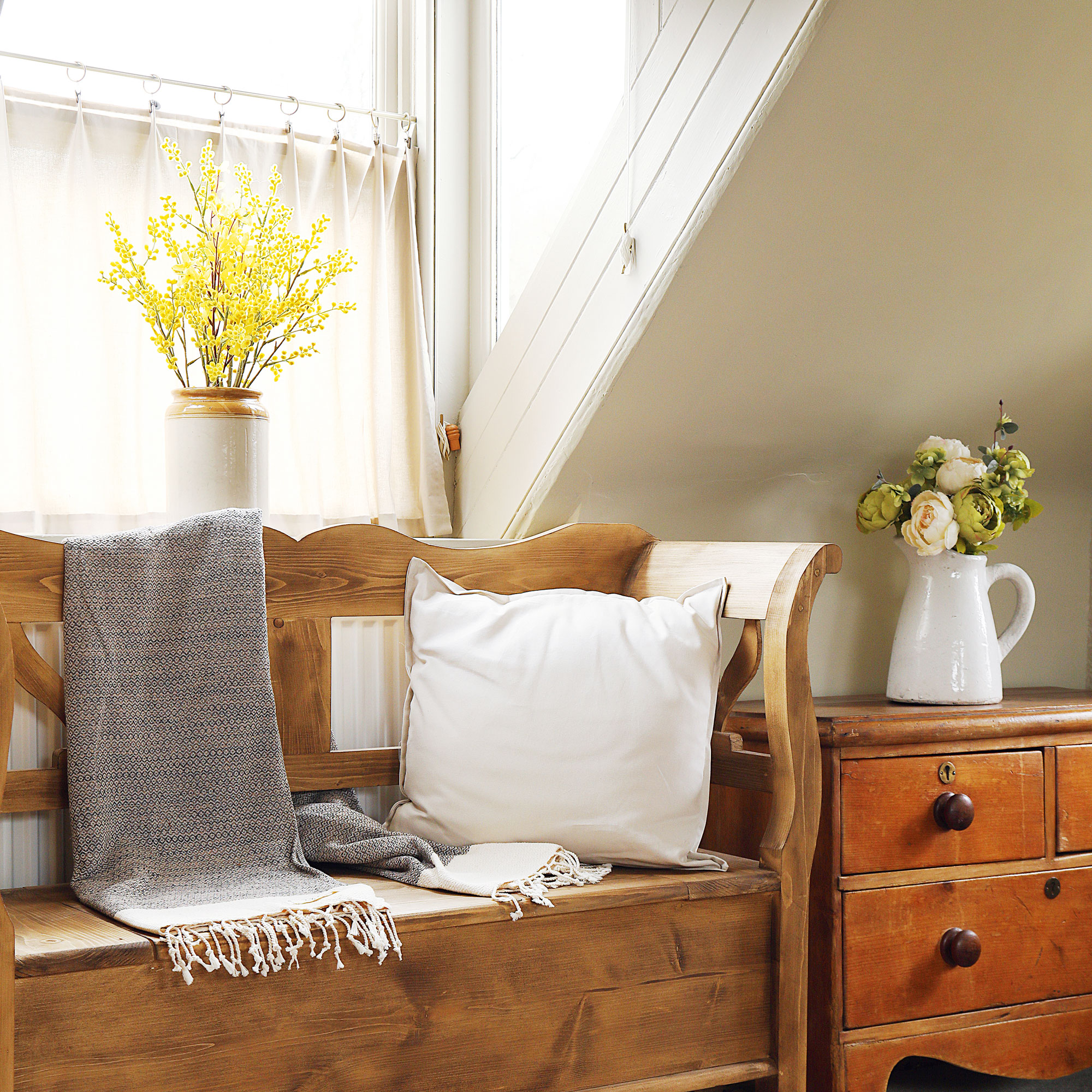 Cream room with wooden storage bench and a linen cafe curtain.