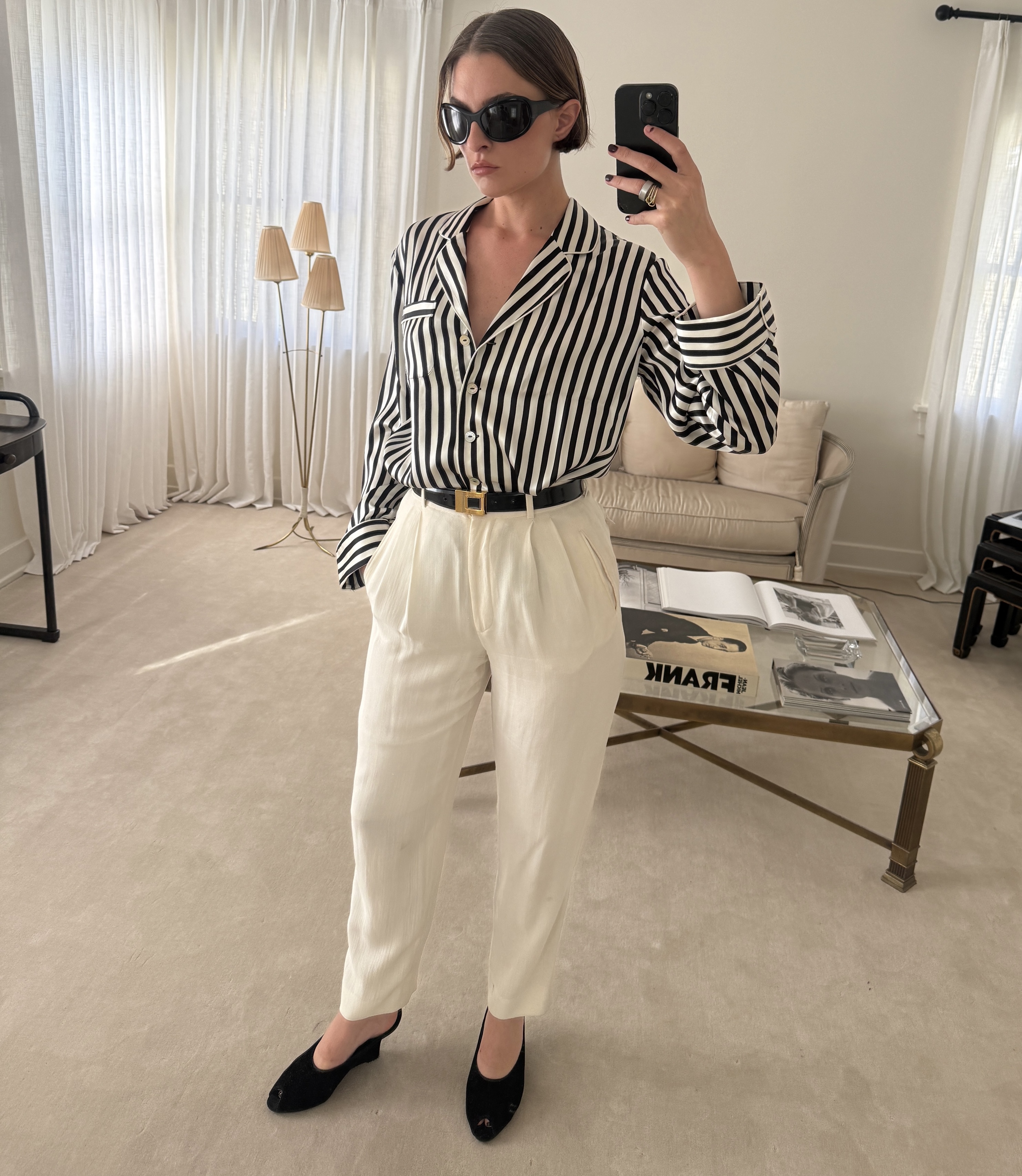 Mirror selfie of Christie Tyler wearing a striped sleep shirt with white pants and low black wedges