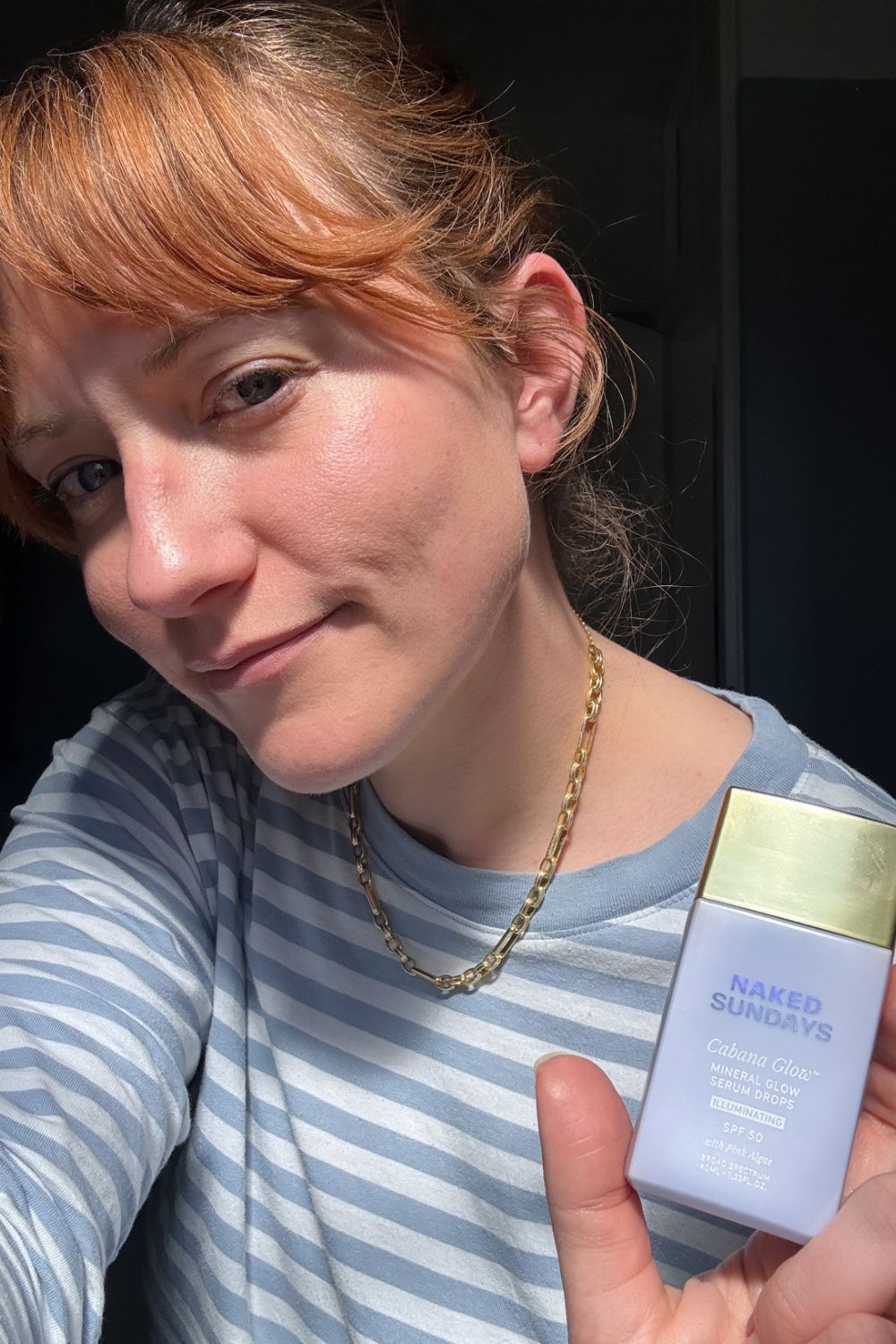 a headshot of matilda with a bottle of naked sundays spf serum