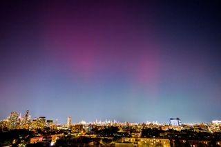 Green and pink lights over a cityscape