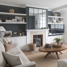 Blue-painted living room with white shelves and fireplace surround, neutral sofas and large mirror above fireplace