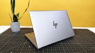 HP ZBook Studio 16 G11 mobile workstation on a white desk with a black table mat, against a yellow backdrop.