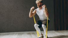 A man performing squats with a resistance band