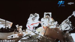 China's Shenzhou 13 astronauts Zhai Zhigang and Wang Yaping wave to a camera during their mission's first spacewalk on Nov. 7, 2021 at the Tiangong space station core module Tianhe.