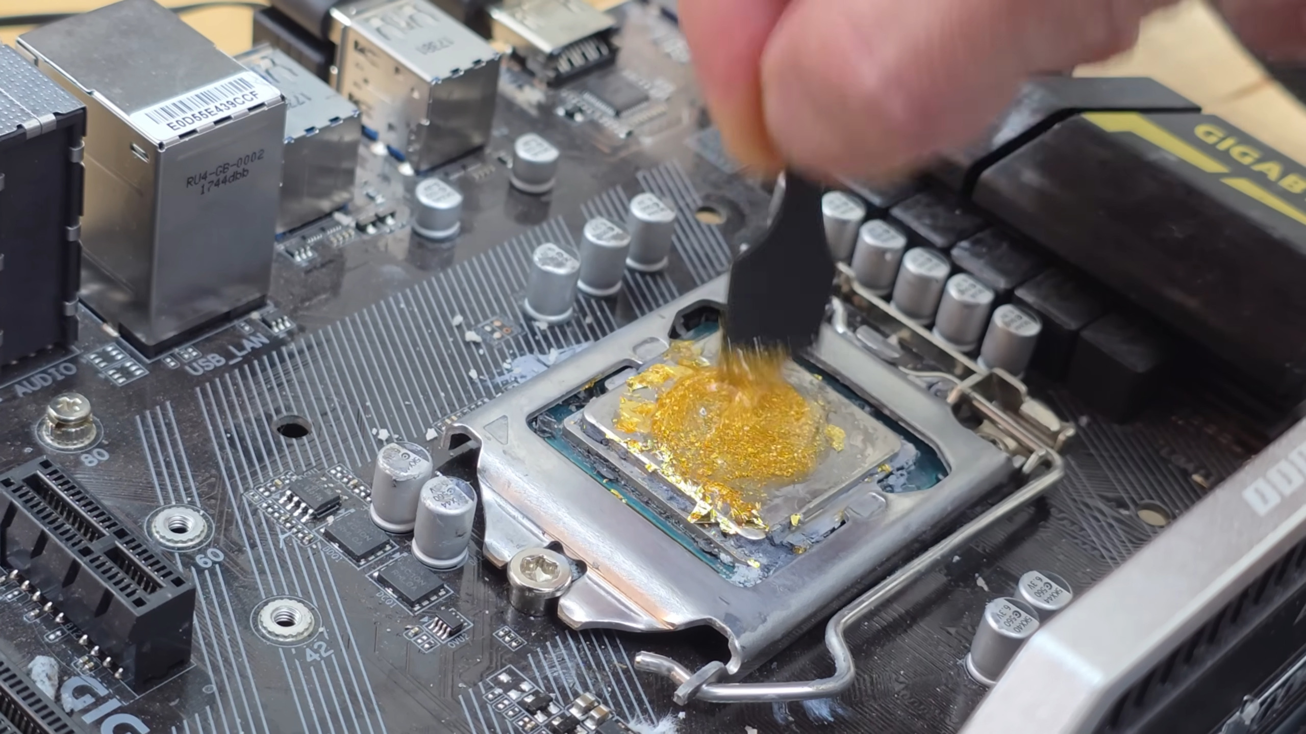 Gold leaf and honey being mixed on top of a CPU as a substitute, edible, thermal paste