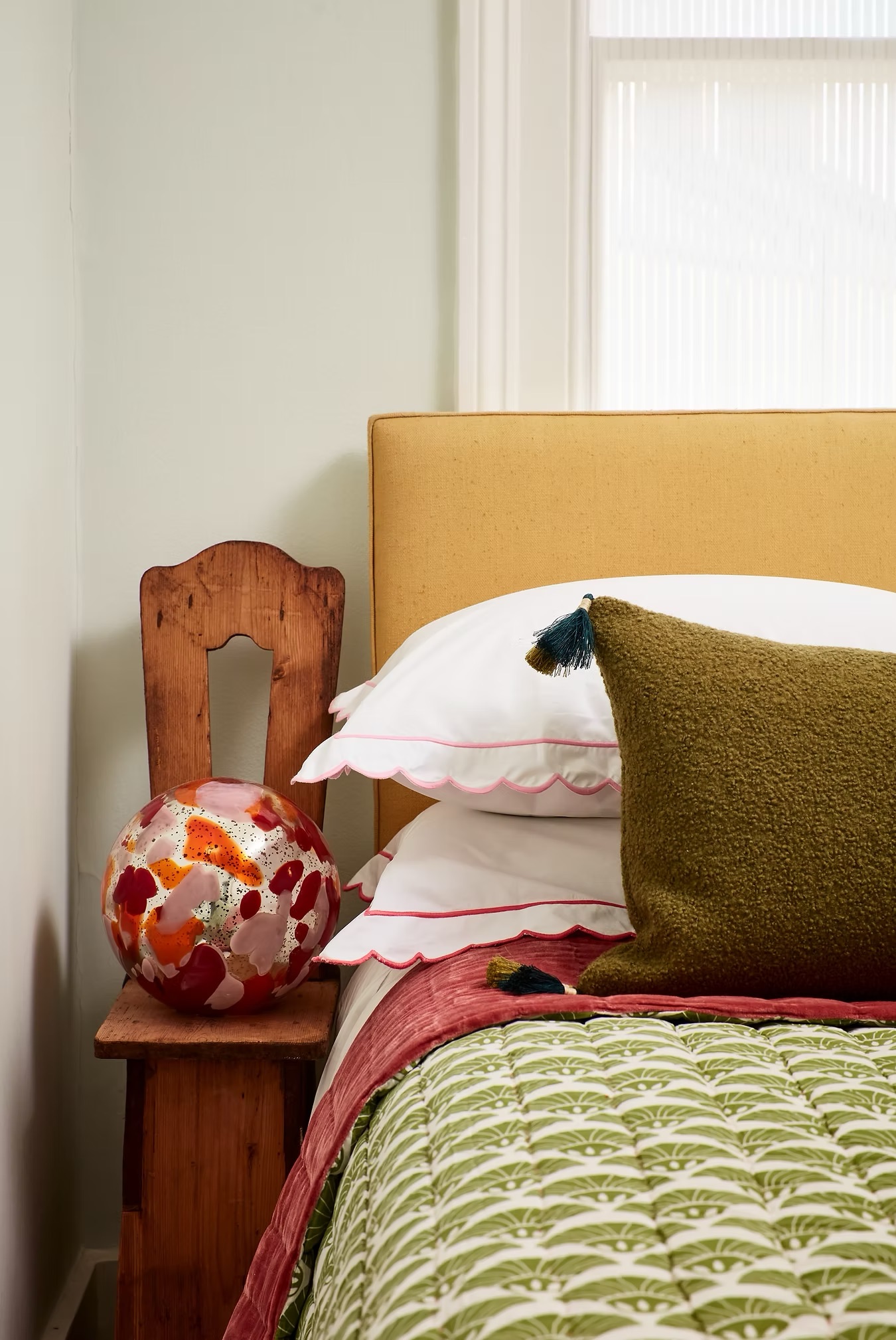 A bedroom with colourful bedding, a yellow headboard, and decorative objects