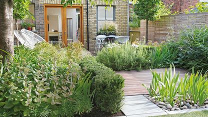 back garden with decked area, paving and planting and grey outdoor chairs