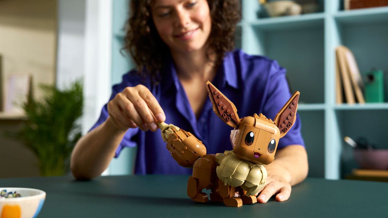 Lego Eevee's tail being lifted by a woman seated at a table