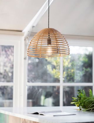 Single pendant feature light made from bamboo over a kitchen island with marble countertops