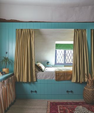 nook bed inbuilt with blue wood surround and green curtains