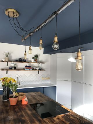 industrial style pendant lighting strung around a metal bar in a industrial style kitchen