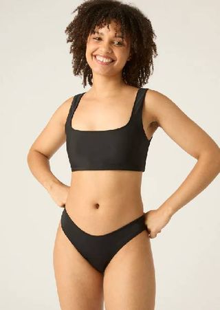 A model wearing a black period bikini from Modibodi.