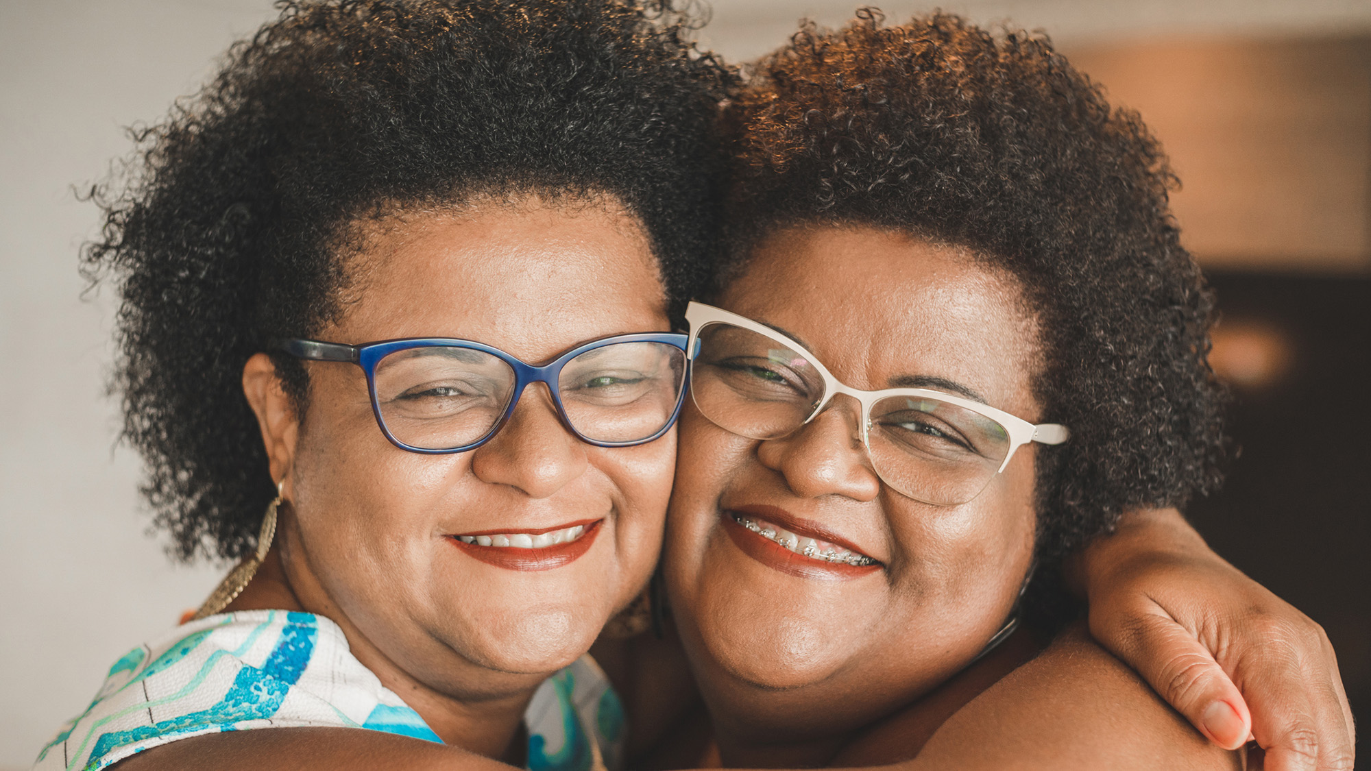 Two women with curly hair smile at the camera.