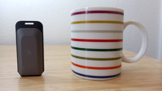 Corsair EX100u portable SSD on desk next to a striped coffee mug