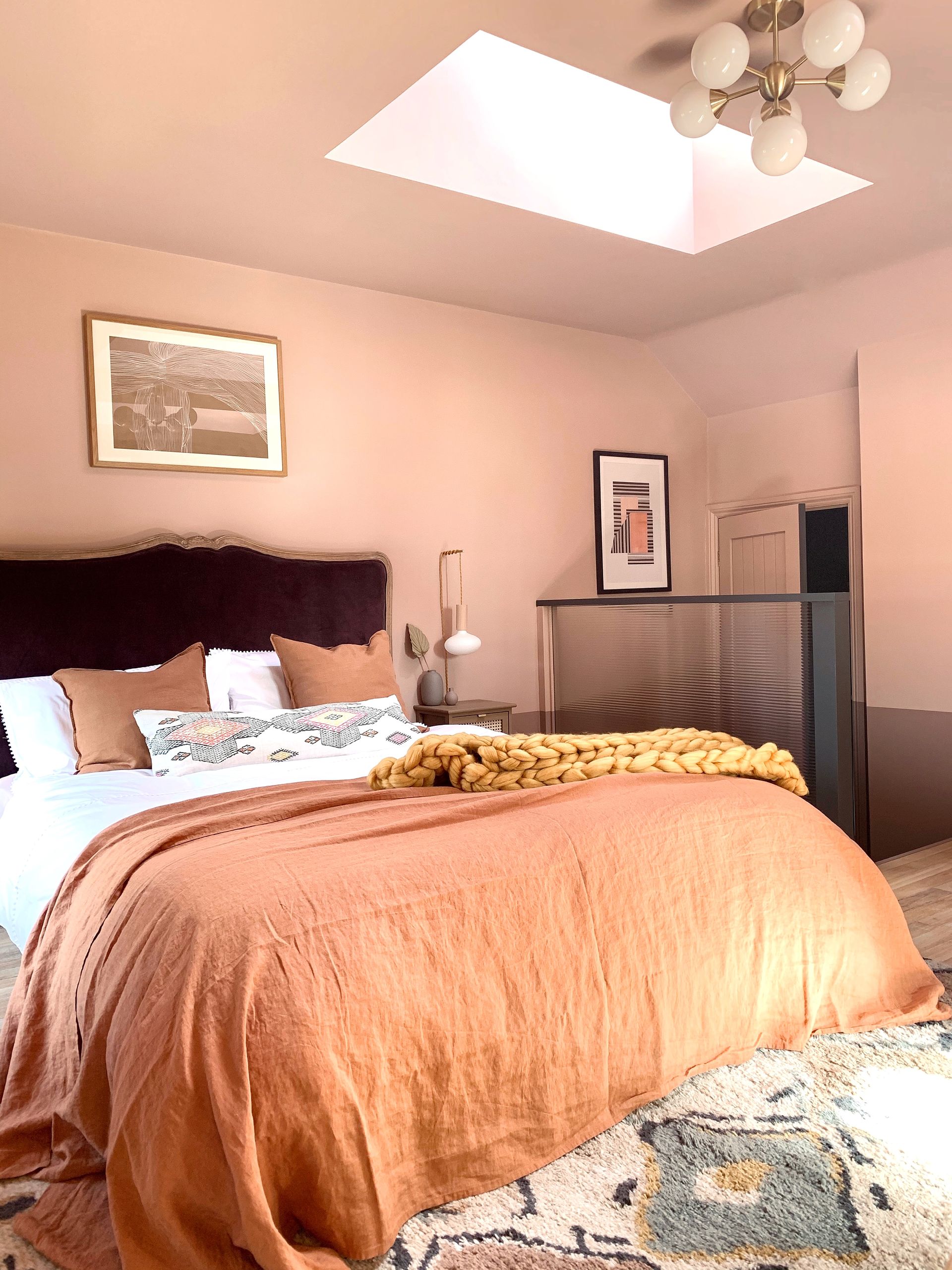 a warm pink bedroom with a rug and dark bedding
